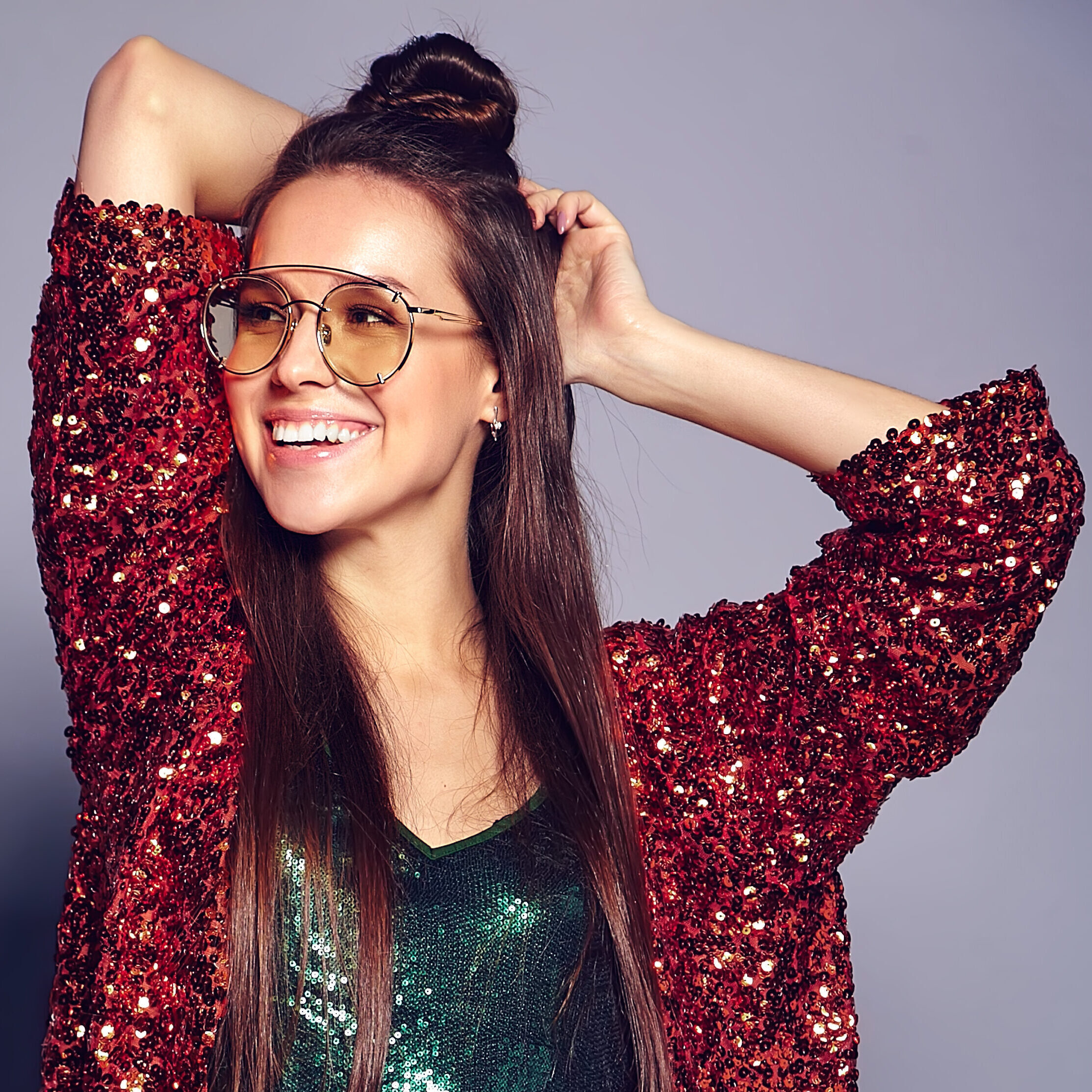 Home beautiful caucasian smiling hipster brunette woman model in bright shinny reflecting summer stylish jacket and green dress posing on gray background